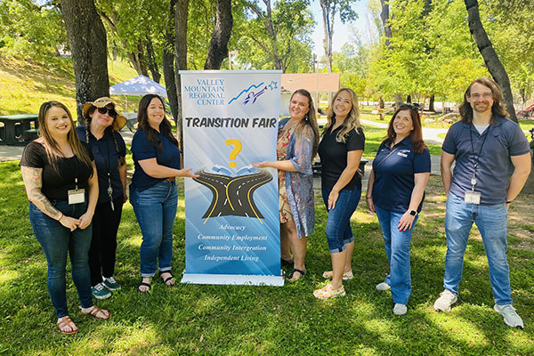 Seven people stand outdoors around a 